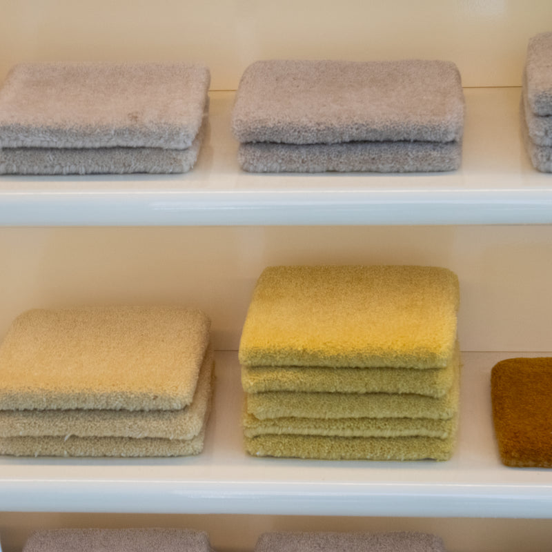 Stacks of textured cushions in various colors on a white shelf.