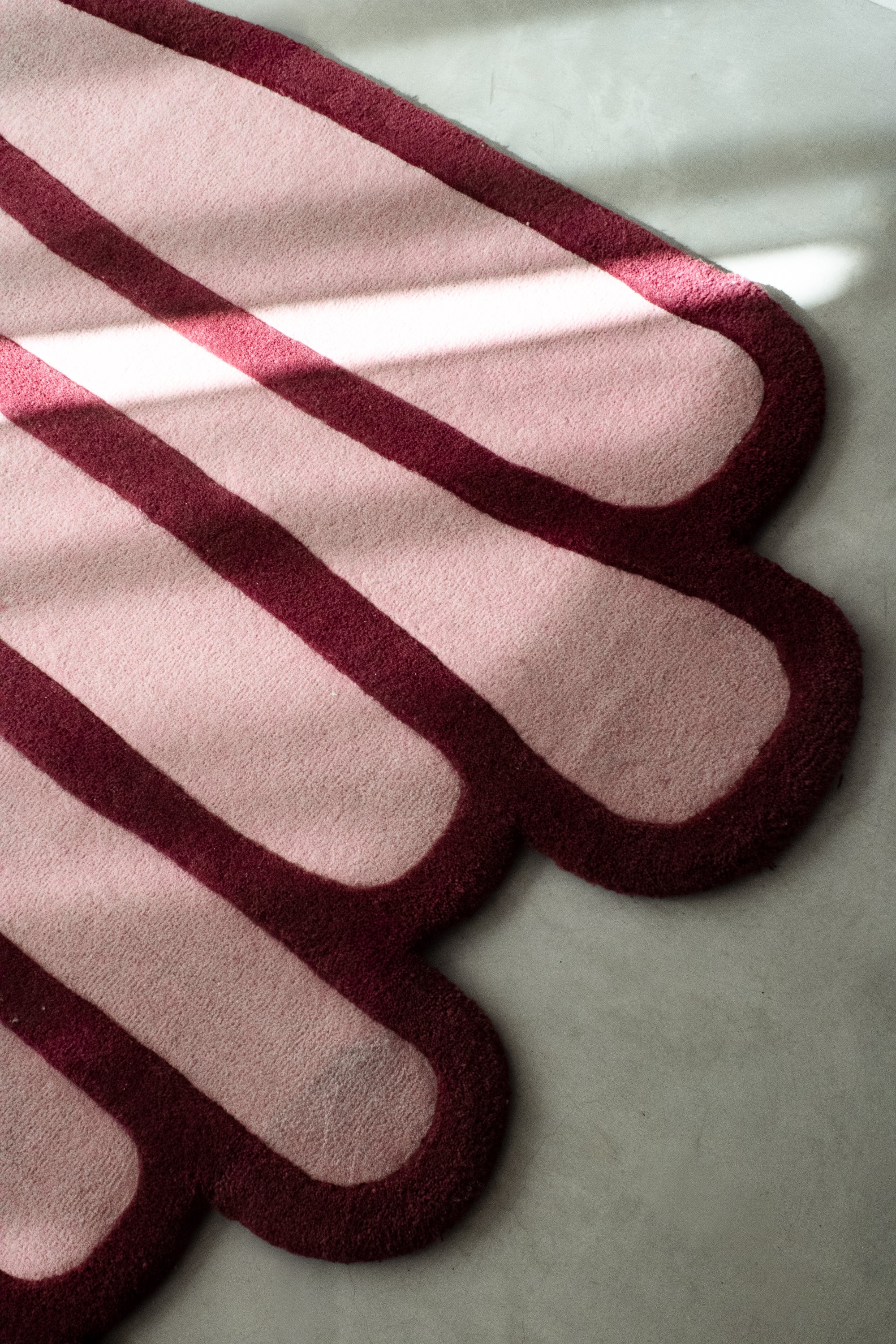 LAYERED wool rug detail showing rounded stacked edges and contrasting burgundy outline