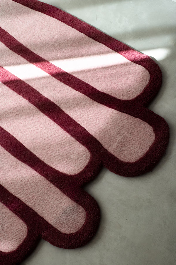 LAYERED wool rug detail showing rounded stacked edges and contrasting burgundy outline